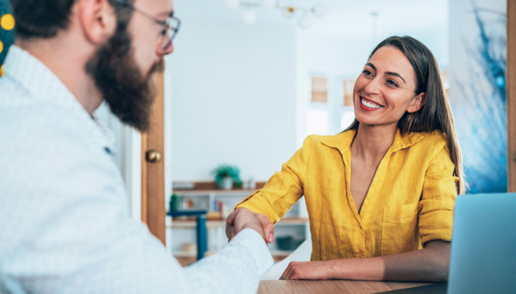 Image of a man and a woman shaking hands at a desk.