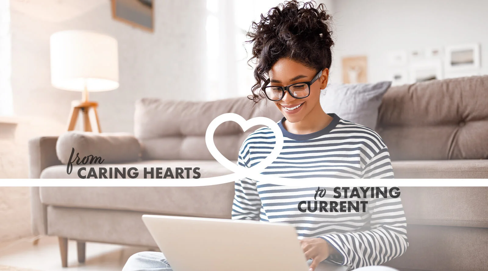 Woman smiling while on floor in front of her sofa on her laptop, with the caption, from caring hearts to staying current