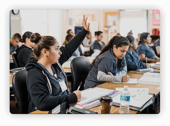 An image of a medical student raising her hand in class to ask a question.