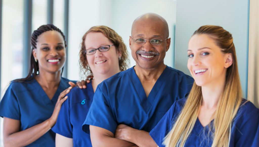 A photo of a group of four healthcare professional smiling at the camera