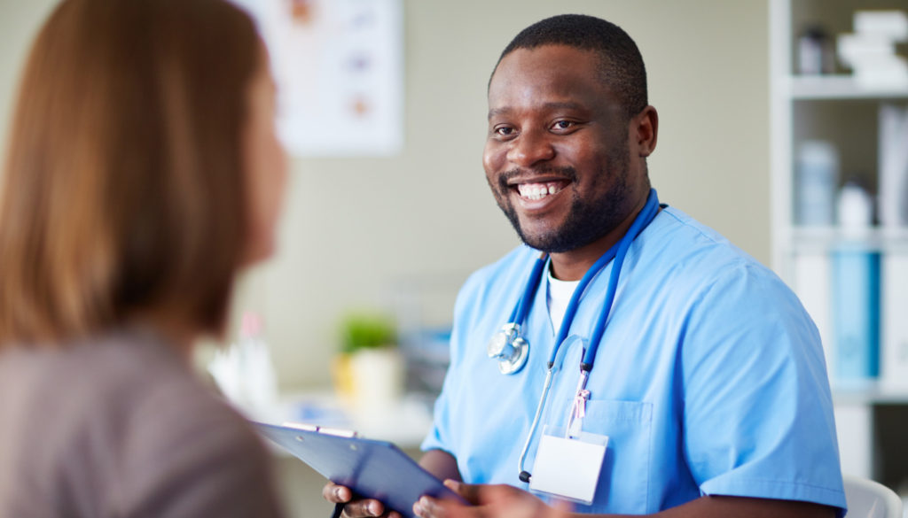 Image of male nurse smiling at another towards camera