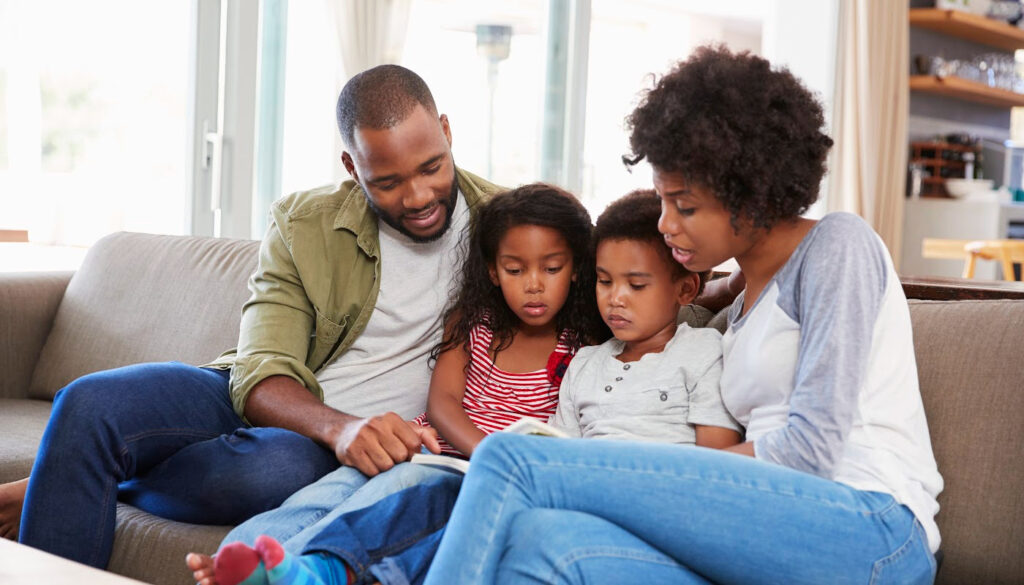 Banner: Family of four sitting on couch reading together, promoting family literacy.