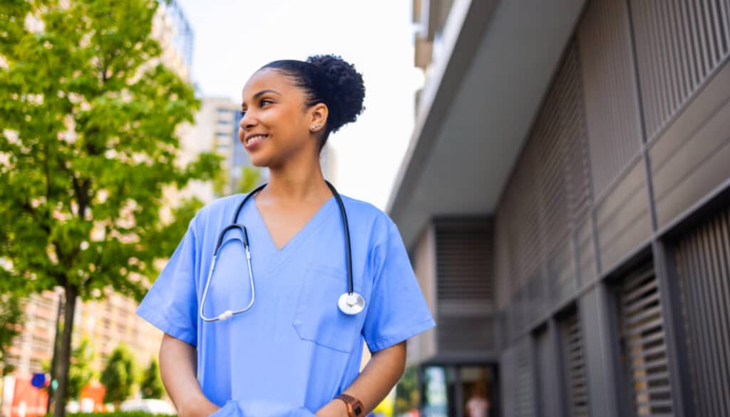 An african-american nurse wearing scrubs and a stethoscope.