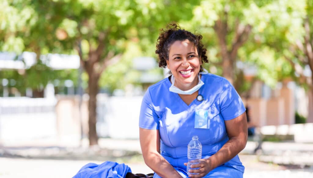 A nurse sitting on a bench with a bottle of water.