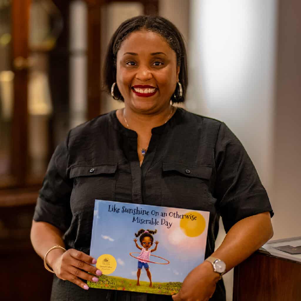 Dr Kelly Byrd holding her children's book for Family Literacy Day