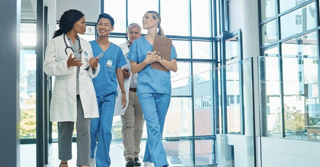 A group of doctors and nurses walking down a hallway.