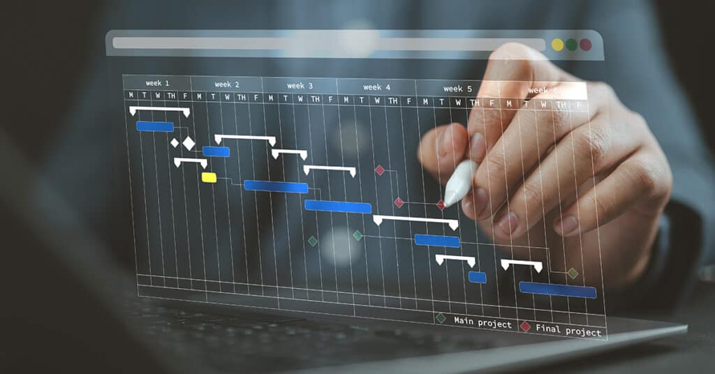 A hand holding a stylus points at a digital Gantt chart on a screen, displaying project tasks and timelines across multiple weeks.